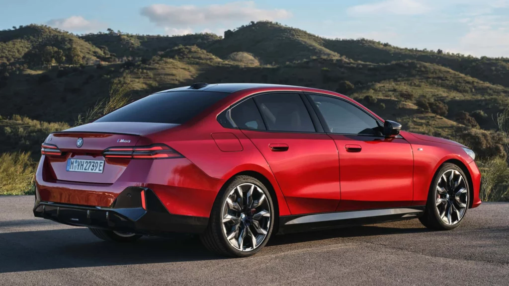 紅色BMW i5 M60電動轎車側視圖,停在山路旁,展示其光滑線條和典雅設計